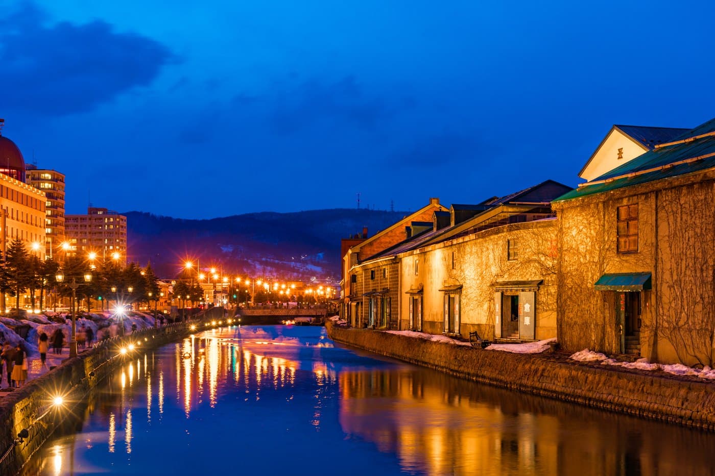 The Otaru Canal at dusk with gas lamps lit and warehouses reflected in the water
