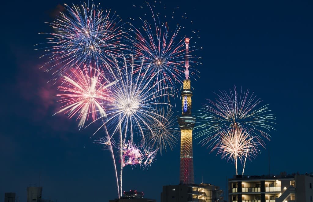 Sumida River fireworks bursting beside the illuminated Tokyo Skytree at night