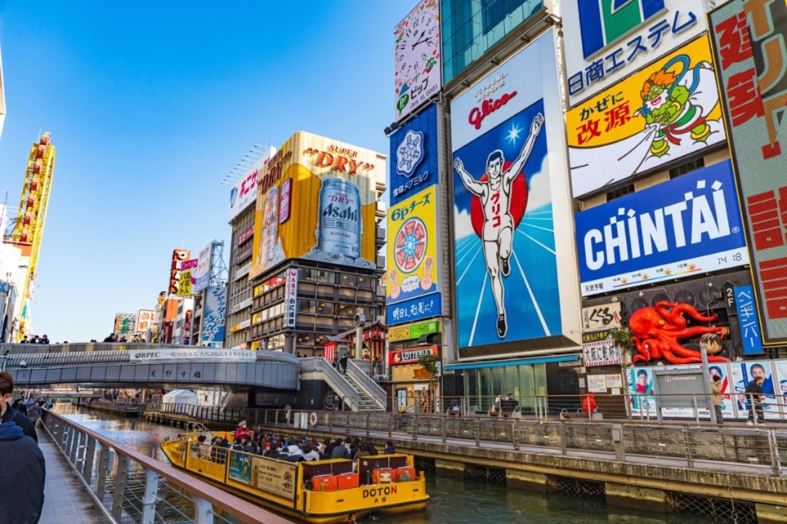 Dotonbori canal in Osaka with the Glico Man sign and yellow sightseeing boat