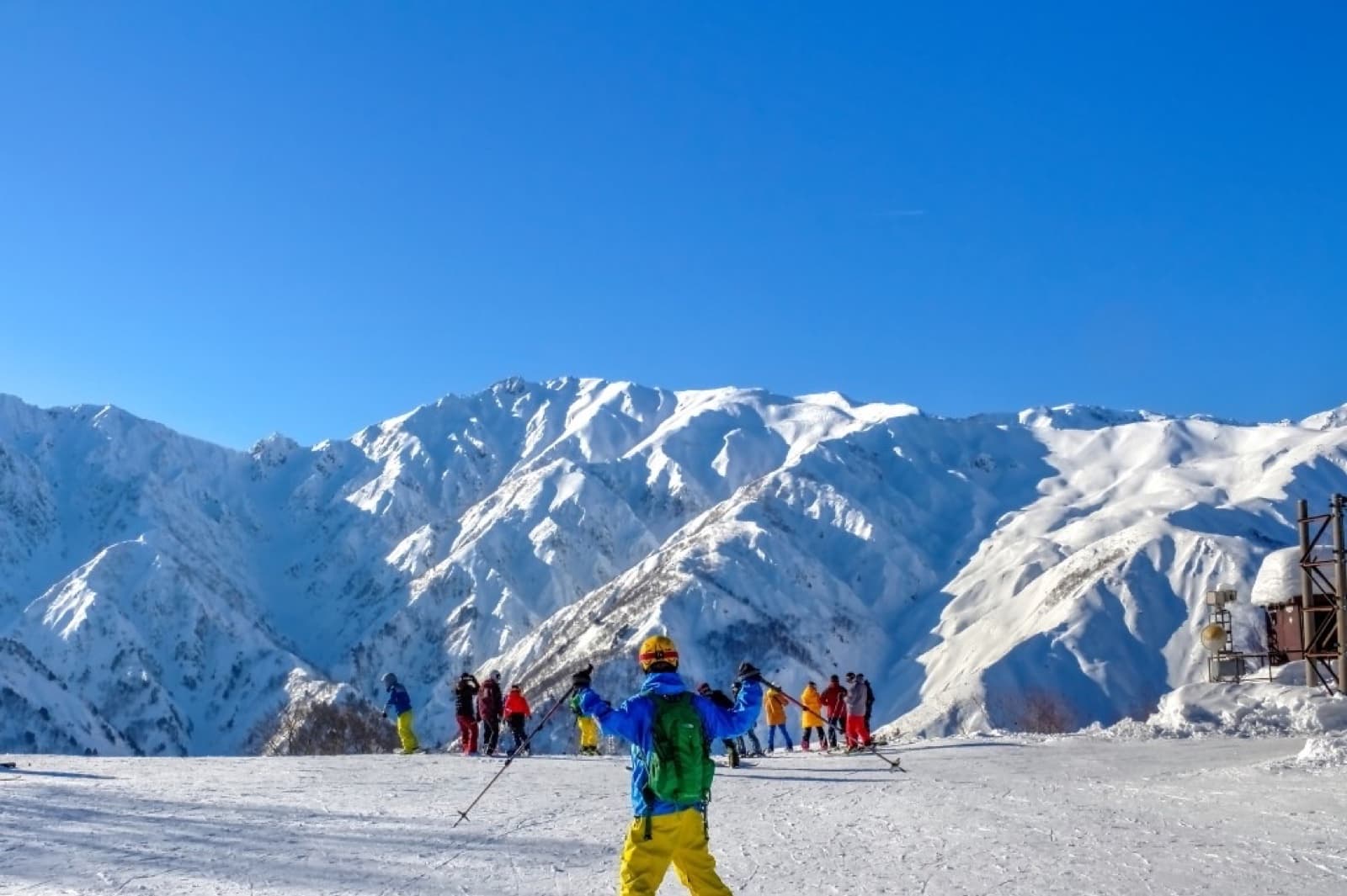 Skier on a snowy plateau overlooking the Hakuba mountain range