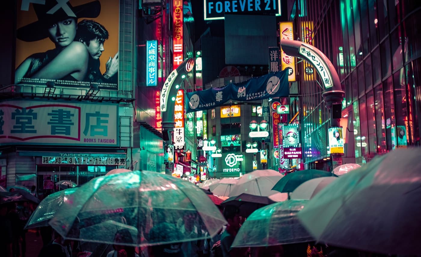Crowd with umbrellas walking on a rainy night street in Shibuya, Tokyo