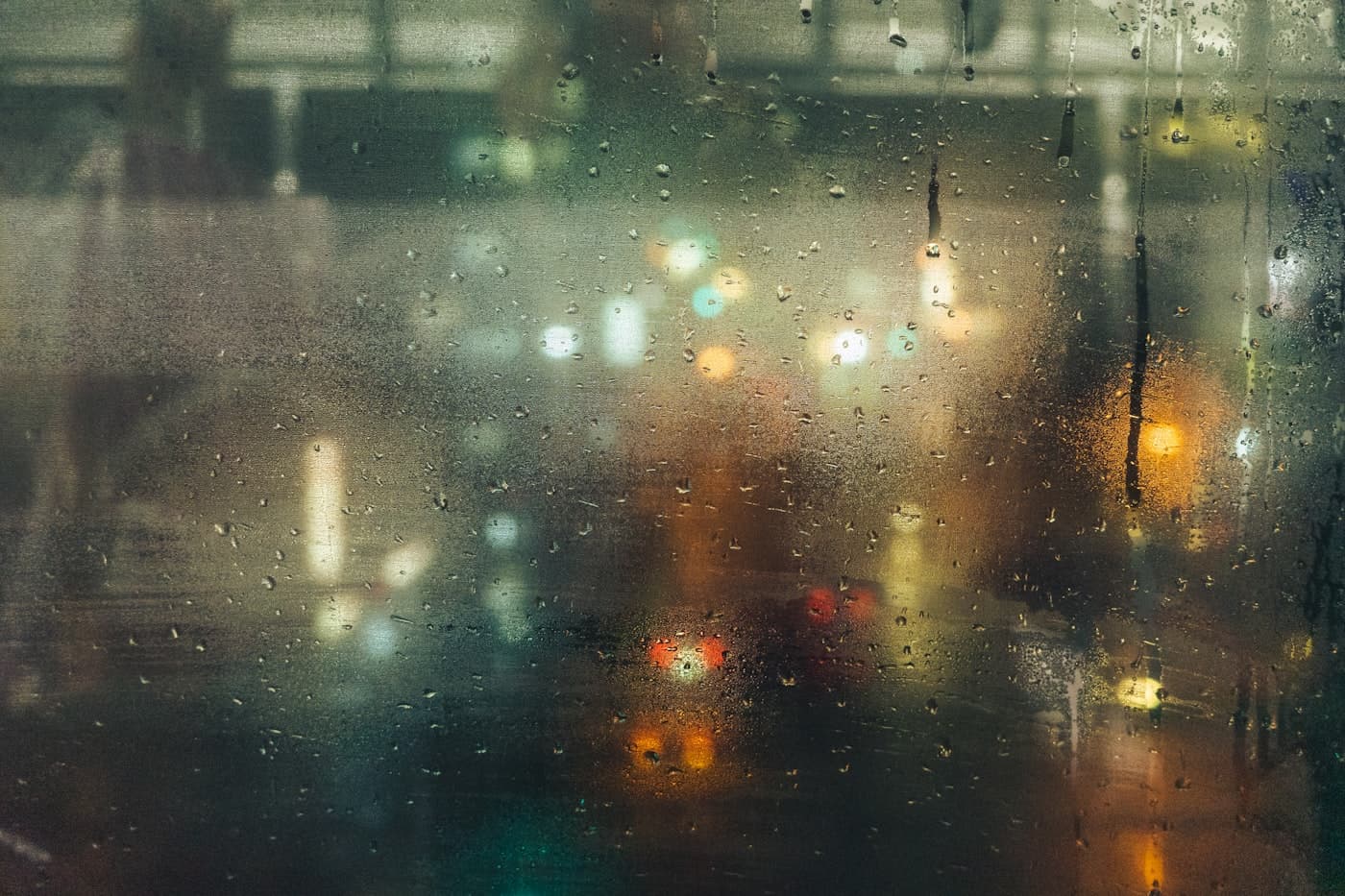Raindrops on a Tokyo window at night, suggesting being safely indoors during a typhoon