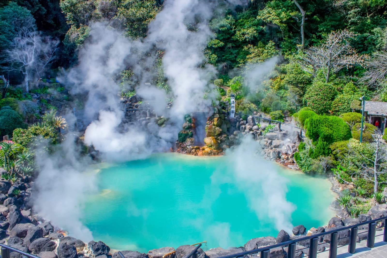 The turquoise Umi-Jigoku hot spring steaming among rocks and greenery at Beppu, Oita