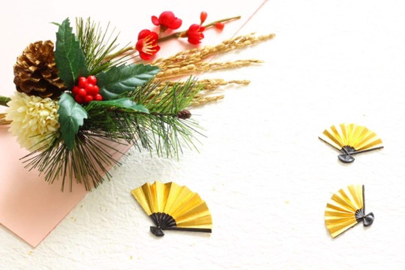 Japanese New Year decorations: pine, red plum blossom, holly berries, a pine cone and small gold folding fans