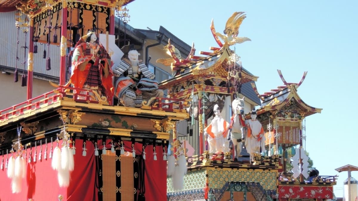 Ornate Takayama festival yatai floats with gold leaf, red fabric and karakuri figures under a clear blue sky
