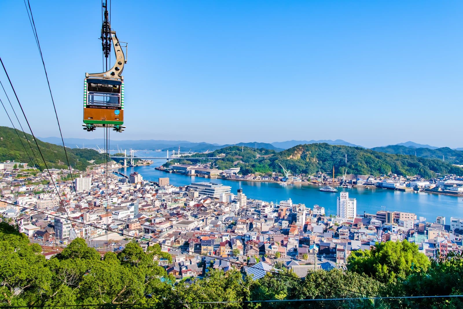 A Senkoji-yama Ropeway gondola above the rooftops of Onomichi, with the narrow strait, its bridges and green islands behind