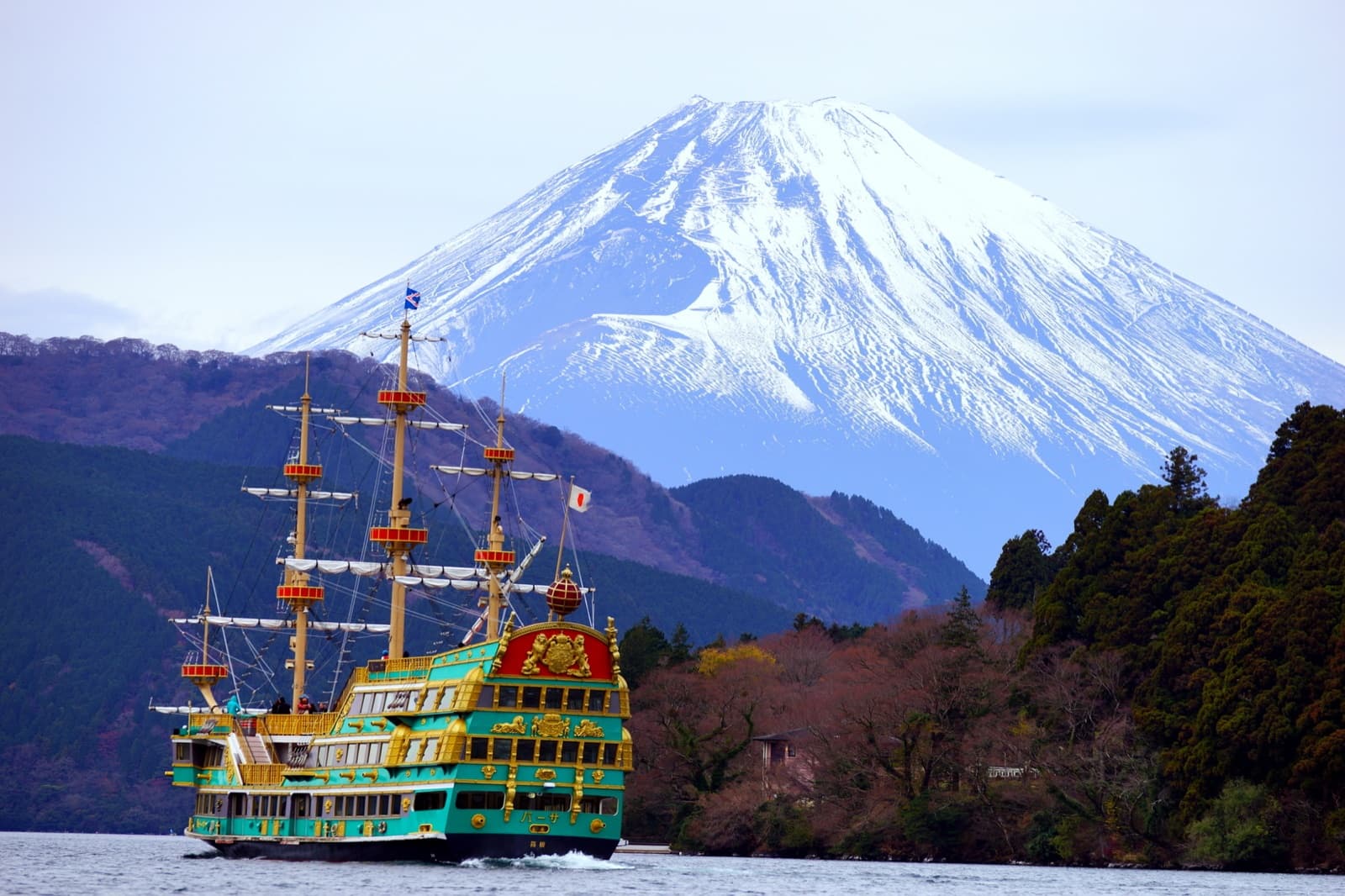 Sightseeing boat crossing Lake Ashi in Hakone with a snow-capped Mount Fuji behind it