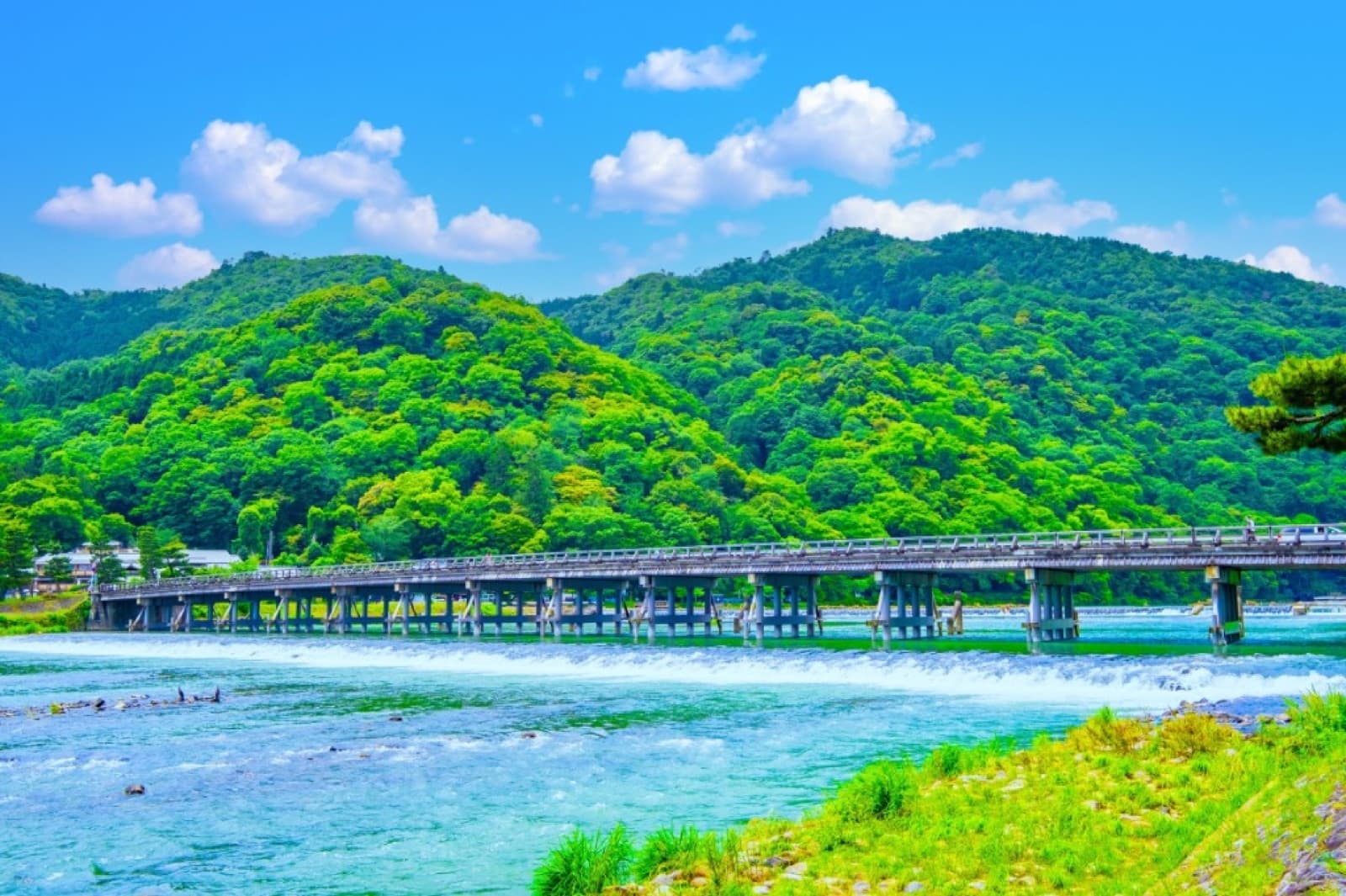 Togetsukyo Bridge over the river at Arashiyama, Kyoto, with green summer mountains behind