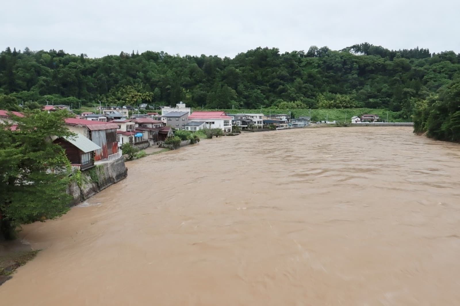 A river running high with muddy floodwater through a Japanese town after heavy typhoon rainfall