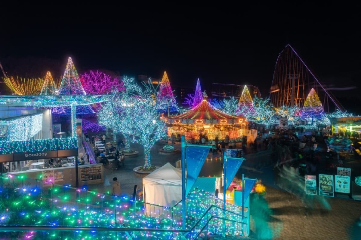 Yomiuriland Jewellumination at night with blue-lit trees, a carousel and colourful light displays across the amusement park