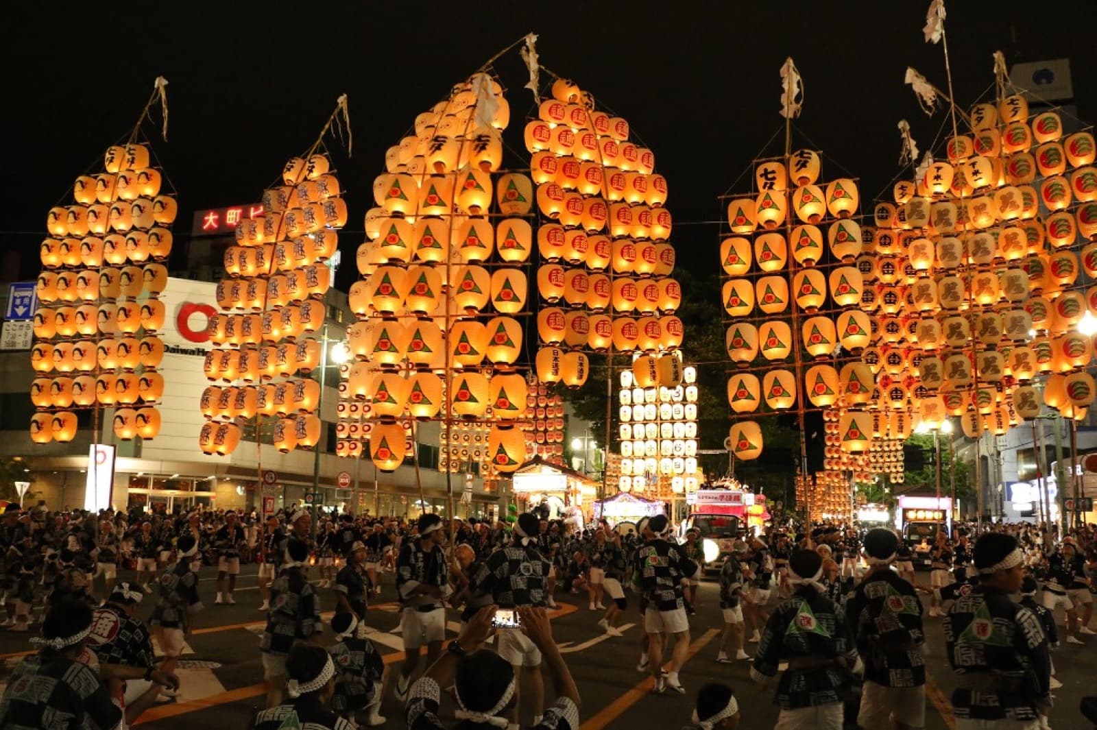 Akita Kanto Matsuri performers balancing tall bamboo poles strung with lit lanterns