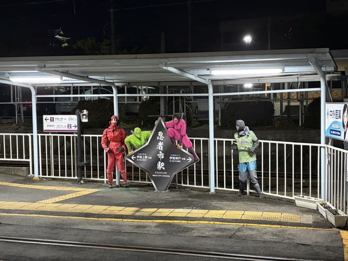 Cut-out ninja figures beside the Ninja City Station sign on the platform at Uenoshi Station in Iga