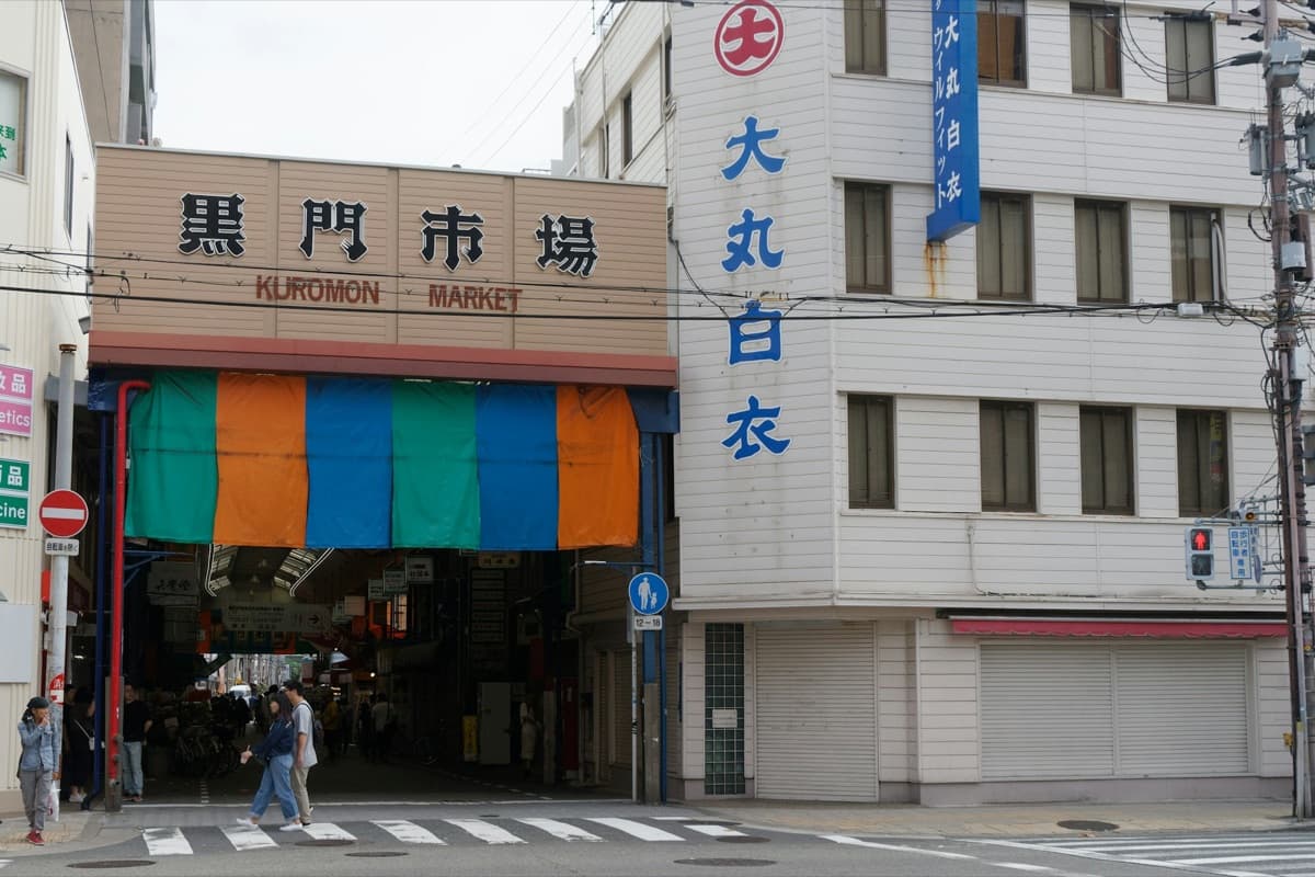 The entrance to Kuromon Market in Osaka with its name sign and colored awnings over the arcade